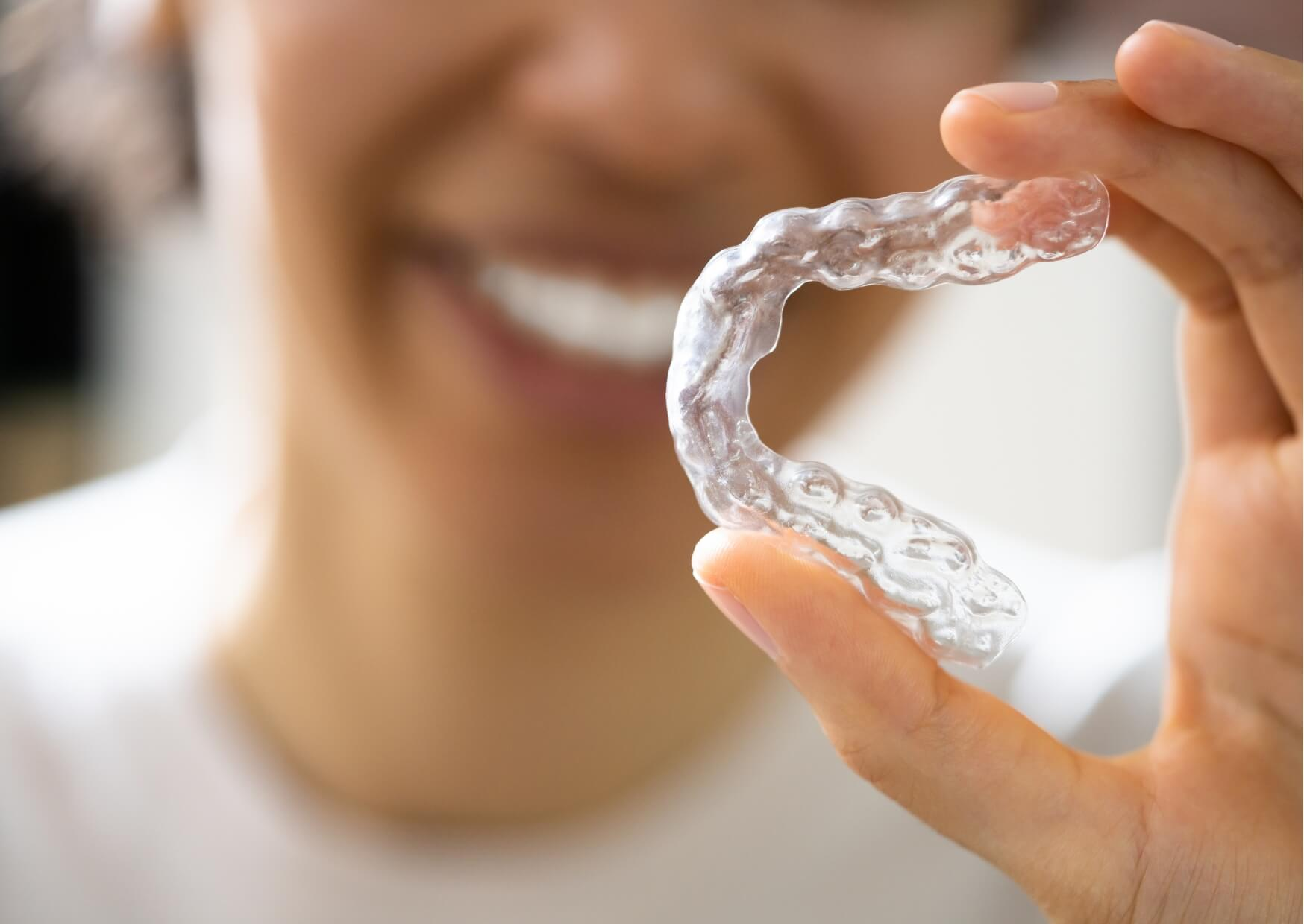 Person holding a custom clear nightguard designed to protect teeth from grinding and clenching during sleep.