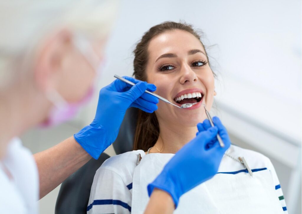 Patient smiling during a first dental appointment while the dentist performs a routine oral examination and discusses oral health