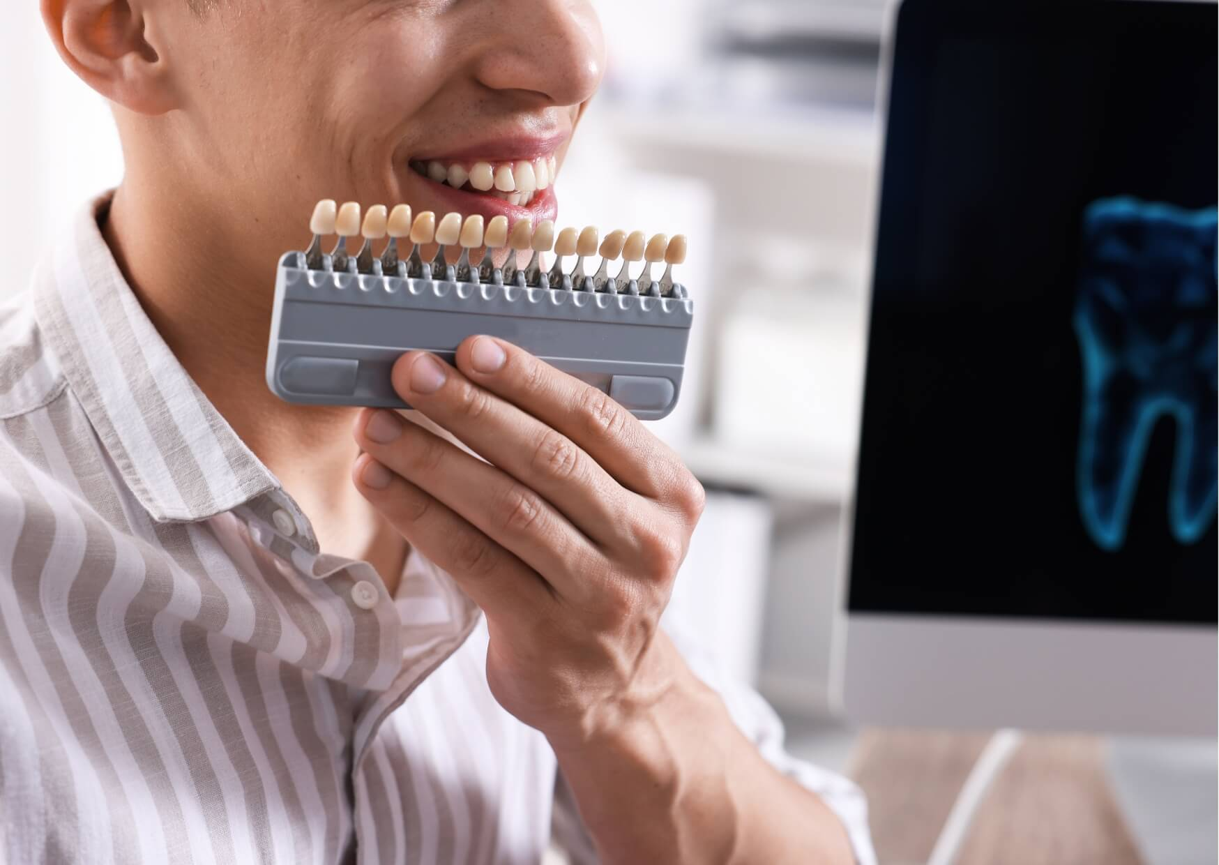 Patient comparing veneer shade samples during a cosmetic consultation, with veneers cost by location varying based on materials and provider.