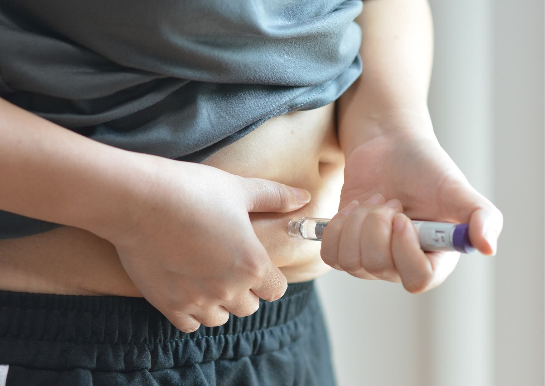 Person using an Ozempic injection pen, highlighting the connection between GLP-1 medications and potential effects on teeth and oral health.